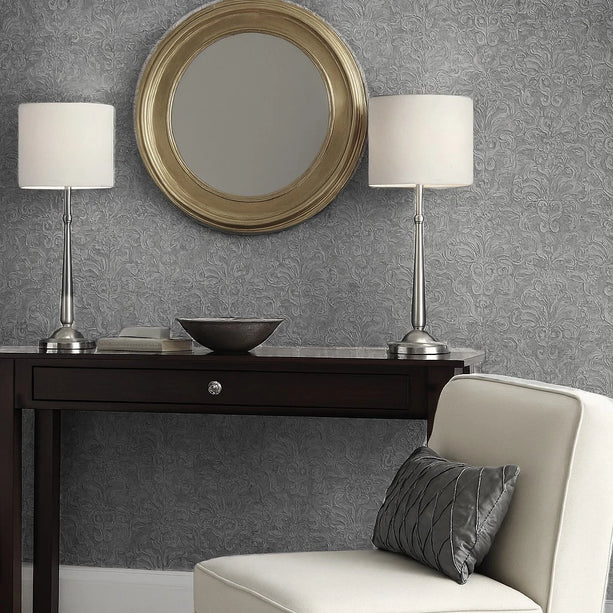 Decorative setup with a round mirror, lamps, and a console table against a patterned wall.